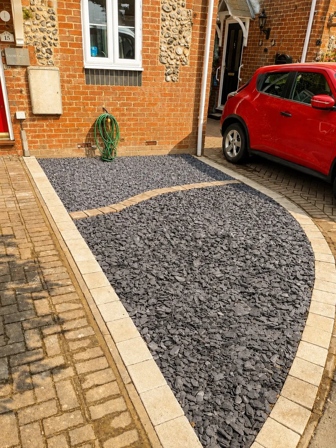 After: the finished Lytchett frontage — two slate beds split by a sweeping paved band, inside a curved kerbed border running down to the existing driveway