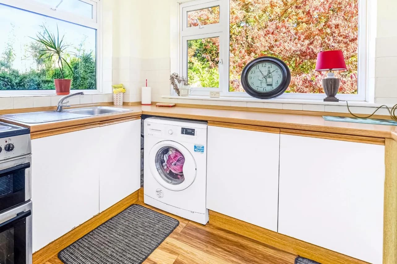 Before: the original kitchen in Parkstone with dated white units, laminate worktops and a freestanding washing machine