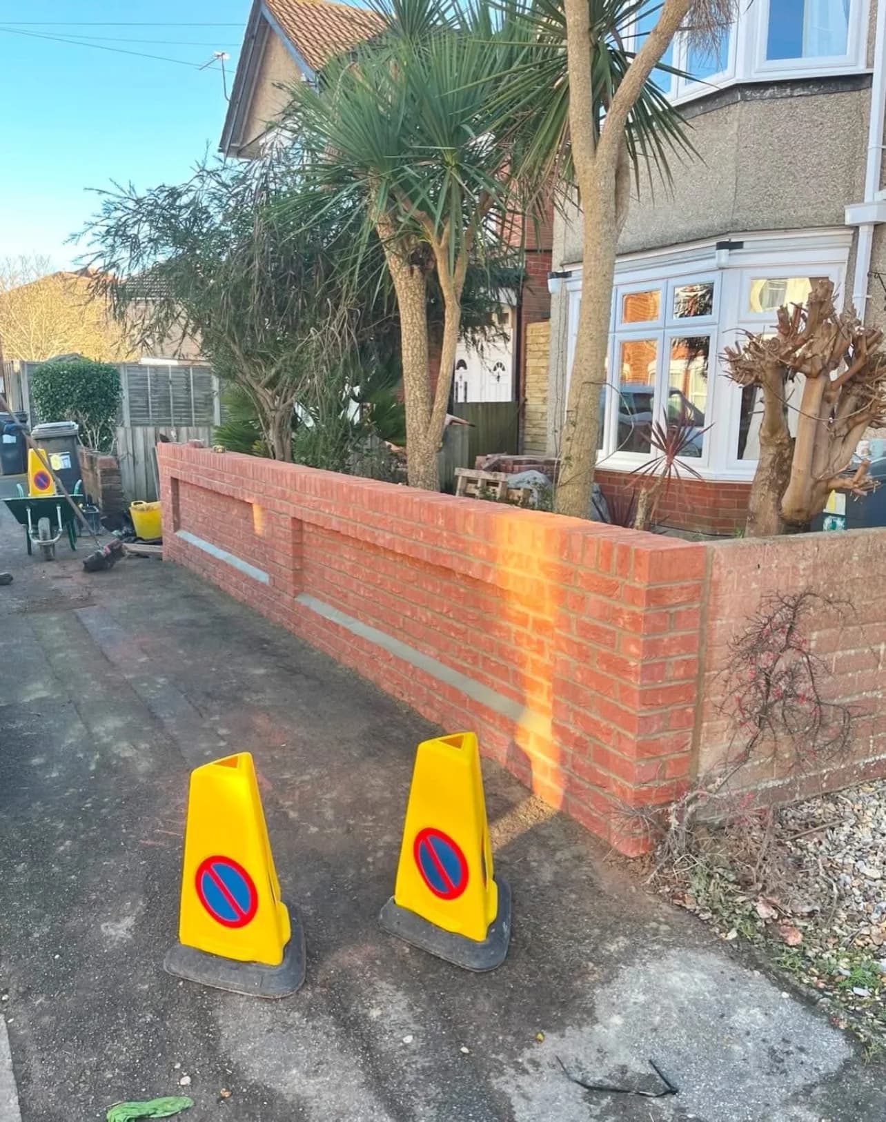 A new brick garden wall built along the boundary of a Charminster property, with the driveway stripped back ready for paving